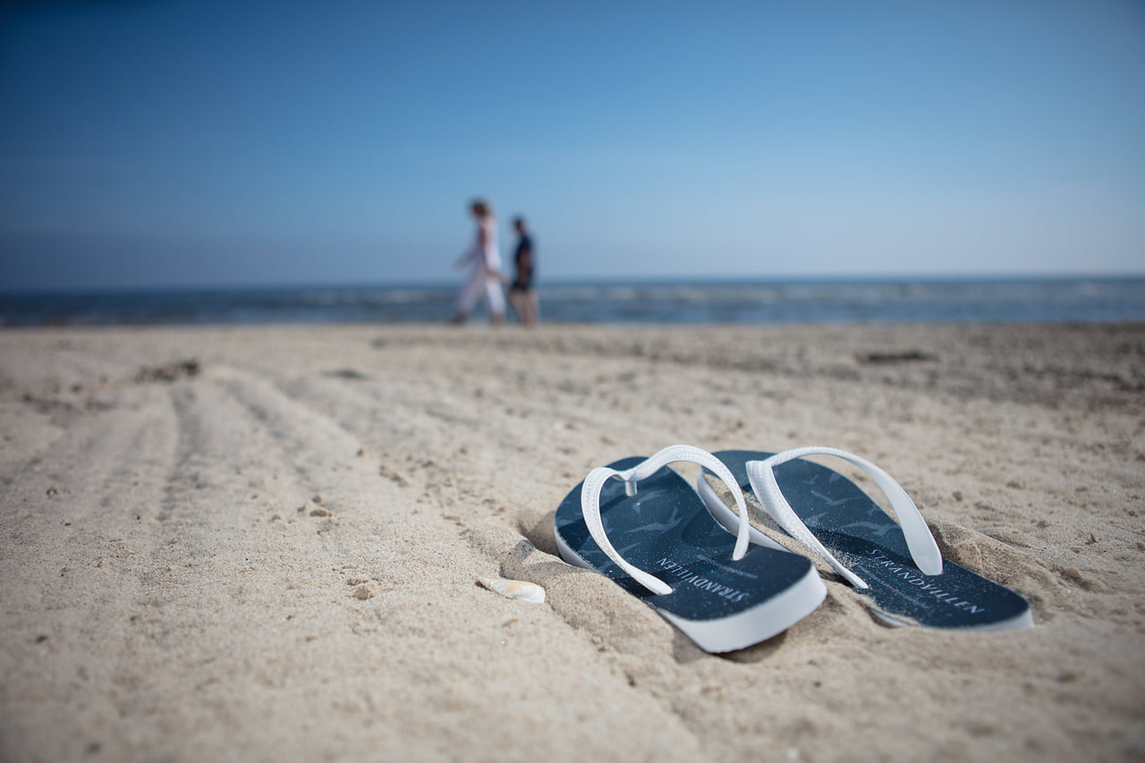 Ein Paar Sandalen im Sand am Strand.